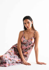 A woman posing in a floral silk gown with a pink base and a digital print that includes a mix of playful animals and graceful foliage.