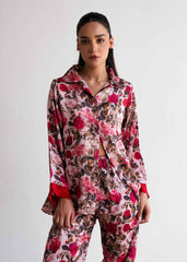 A woman wearing a floral print silk sleepwear set, consisting of a button-up shirt and matching pants.