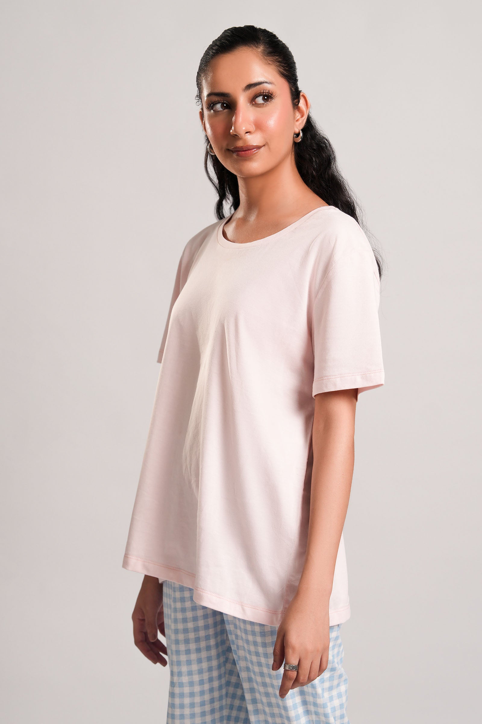 Kelly – LaRosa Night Wears for Women – Cotton Summer Sets Collection | Larosawears | Shop Online – Side View.
Woman wearing a light pink t-shirt and checkered pants on a plain background