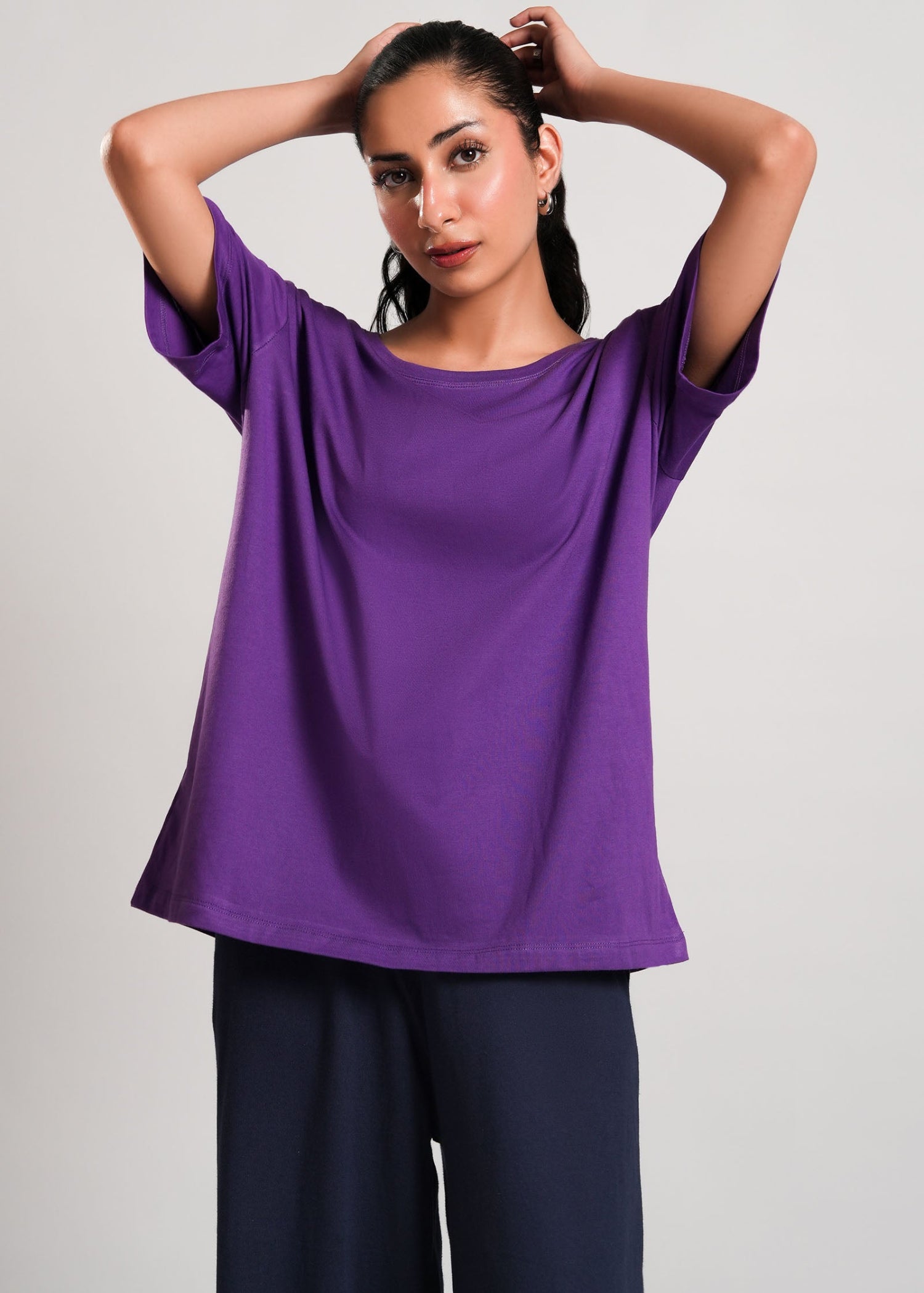 Basic Purple Tee – LaRosa Night Wears for Women – Cotton Summer Sets Collection | Larosawears | Shop Online – Lifestyle Look.
Woman wearing a purple top and dark pants against a plain background