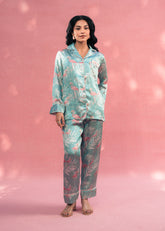 Woman wearing a patterned pajama set against a pink background