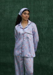 A woman wearing a baby blue silk pajama set with flamingo prints, consisting of a button-down shirt and matching pants. - Larosa pak
