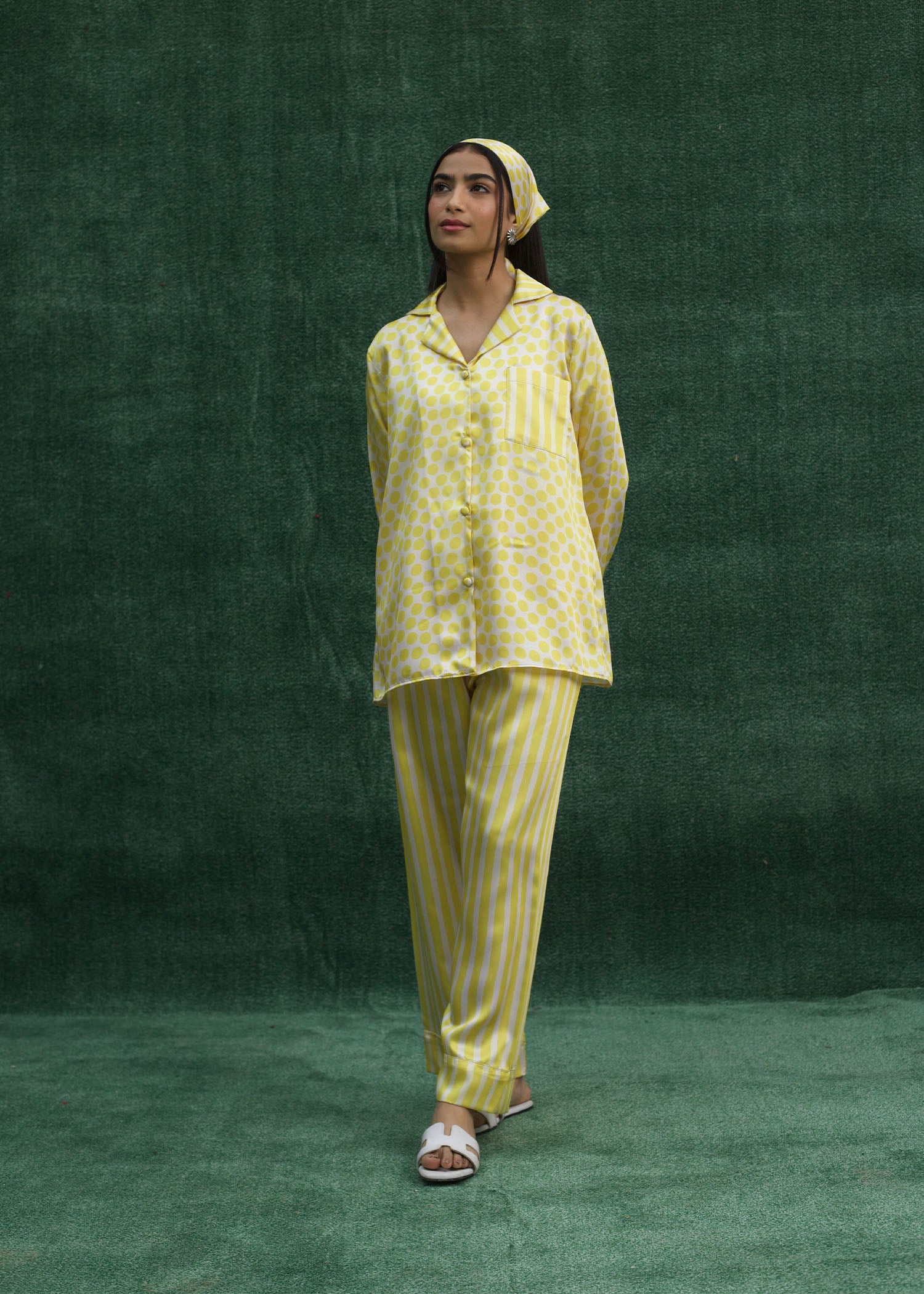 A model wearing a yellow silk pajama set with a mix of striped and polka dot patterns.