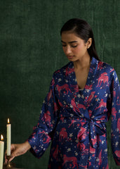 A women standing in a full-length shot, wearing a deep blue gown with vibrant pink tiger prints and a matching waist belt.
