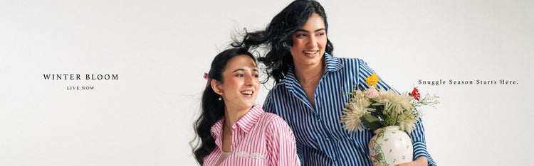 Two models standing together with a flower arrangement, wearing matching striped larosa outfits.
